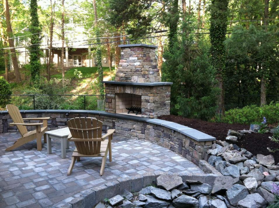 Wooded outdoor living area with chairs and a fireplace in Virginia